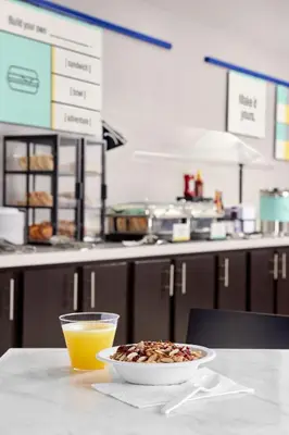 a bowl of cereal and a glass of orange juice on a table at Garner Hotel Mahwah by IHG in Mahwah