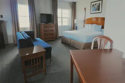 a hotel room with a bed and a chair and a table at Host Inn an All Suites Hotel in Wilkes-Barre