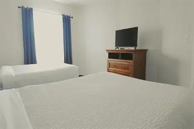 a bedroom with two beds and a tv on a dresser at Host Inn an All Suites Hotel in Wilkes-Barre