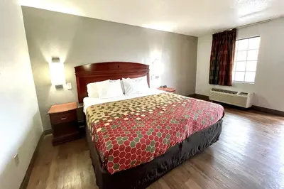 a hotel room with a bed with a red bedspread at Red Carpet Inn Philadelphia Airport in Lester