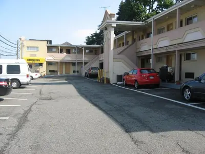 a parking lot with cars parked in front of a building at Domino Inn in North Bergen