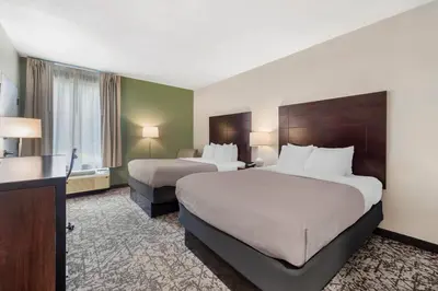a hotel room with two beds and a desk at Quality Inn & Suites NJ State Capital Area in Morrisville