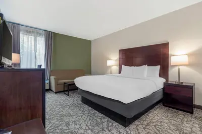 a hotel room with a large bed and a chair at Quality Inn & Suites NJ State Capital Area in Morrisville
