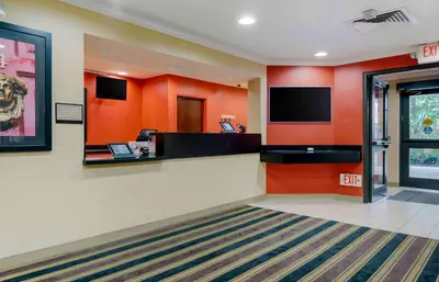 a lobby with orange walls and a flat screen tv at Extended Stay America Suites - Elizabeth - Newark Airport in Elizabeth