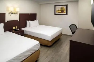 a hotel room with two beds and a desk at Skyview Motel in Fort Lee