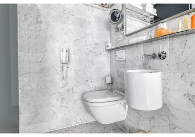 a white bathroom with a toilet and a phone at Hotel Alameda, Highline in New York