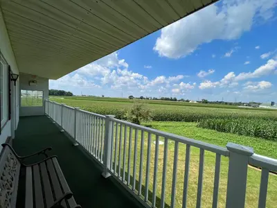 a porch with a bench and a view of a field at Scottish Inns Ronks in Ronks