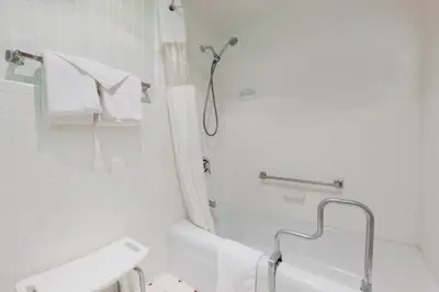 a white bathroom with a shower and a sink at Red Carpet Inn & Suites in Hazleton