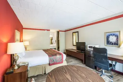 a hotel room with a bed and a desk and a table at Red Carpet Inn & Suites in Hazleton