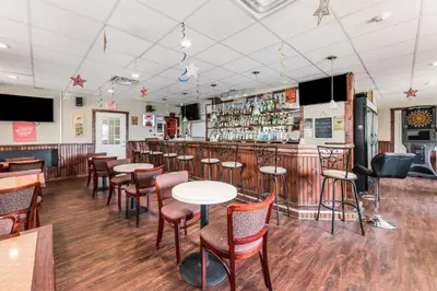 a bar in a restaurant with tables and chairs at Red Carpet Inn & Suites in Hazleton