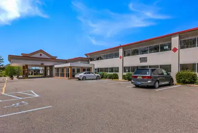 a large building with two cars parked in a parking lot at Red Carpet Inn & Suites in Hazleton