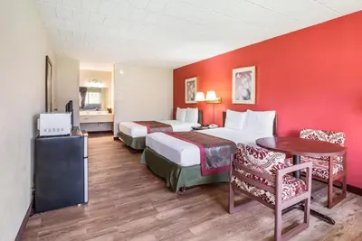 a hotel room with two beds and a table and chairs at Red Carpet Inn & Suites in Hazleton