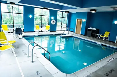 a large swimming pool with blue walls and yellow chairs at Holiday Inn Express & Suites Harrisburg West in Mechanicsburg