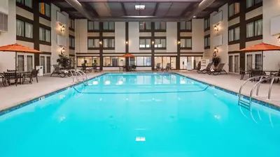 a large pool in a hotel with tables and chairs at Best Western Premier the Central Hotel & Conference Center in Harrisburg