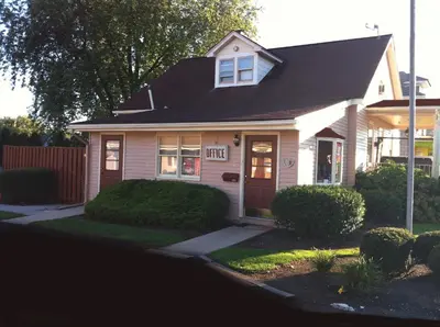 a white house with a brown door and bushes at Cocoa Country Inn Hershey in Hershey