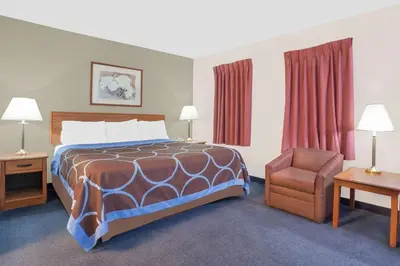 a hotel room with a bed and a chair at Super 8 by Wyndham Middletown in Middletown