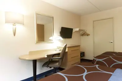 a hotel room with a desk and a bed and a bed and a room with at Days Inn by Wyndham Monmouth Junction-S Brunswick-Princeton in Monmouth Junction