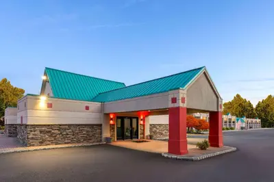 a building with a green roof and red columns at Ramada by Wyndham Parsippany in Parsippany