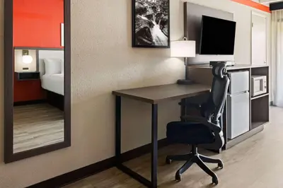 a room with a desk with a chair and a mirror at Ramada by Wyndham Parsippany in Parsippany