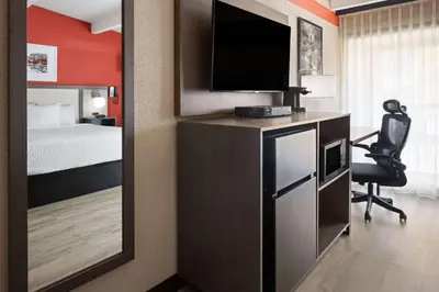 a room with a bed and a desk with a television at Ramada by Wyndham Parsippany in Parsippany