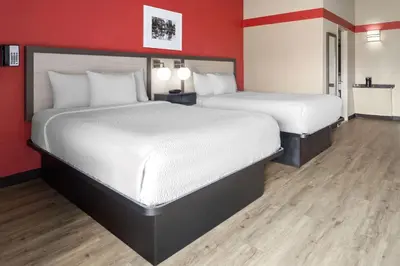 two beds in a room with red walls and wooden floors at Ramada by Wyndham Parsippany in Parsippany