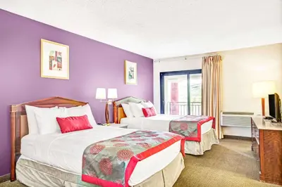 two beds in a hotel room with purple walls at Ramada by Wyndham Rockaway in Rockaway