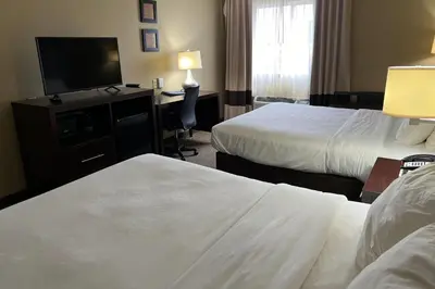 a hotel room with two beds and a television at Days Inn & Suites by Wyndham Manheim Lebanon in Manheim