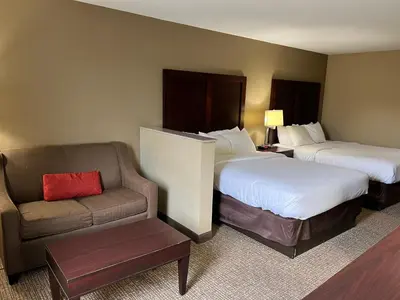 a hotel room with two beds and a couch at Days Inn & Suites by Wyndham Manheim Lebanon in Manheim