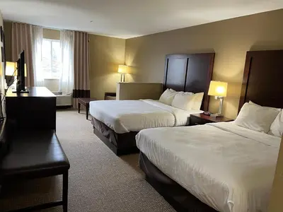 a hotel room with two beds and a desk at Days Inn & Suites by Wyndham Manheim Lebanon in Manheim