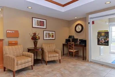 a waiting room with chairs and a desk and a clock at Candlewood Suites Elmira Horseheads by IHG in Horseheads