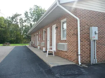 a red brick building with a window and a chair at Red Rose Motel in Elizabethtown
