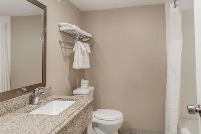a bathroom with a toilet and a sink and a mirror at Pocono Inn & Banquet - Stroudsburg in Delaware Water Gap