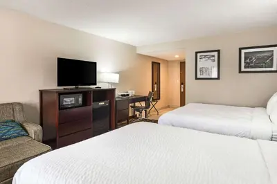 a hotel room with two beds and a desk with a television at Pocono Inn & Banquet - Stroudsburg in Delaware Water Gap