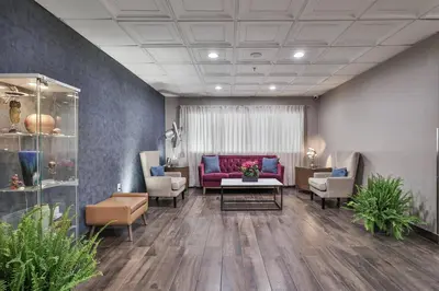 a waiting room with a red couch and chairs at The Penn Stroud, Stroudsburg - Poconos, an Ascend Collection Hotel in Stroudsburg