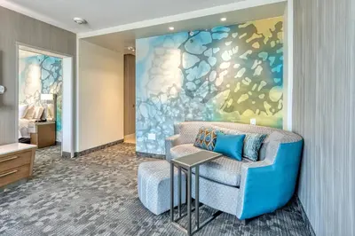 a living room with a blue couch and a painting at Courtyard by Marriott North Brunswick in North Brunswick