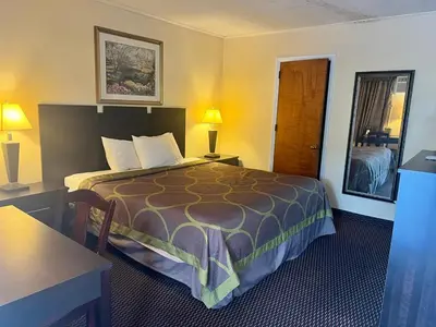 a hotel room with a bed and a table and lamps at Budget Host Inn in New Berlinville