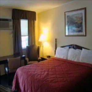 a hotel room with a red bed and a chair at Budget Host Inn in New Berlinville