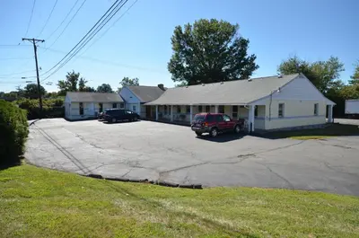 a house with a car parked in a driveway at Budget Host Inn in New Berlinville