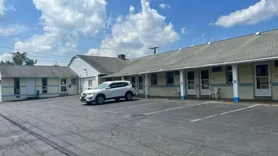 a white car parked in a parking lot in front of a building at Budget Host Inn in New Berlinville