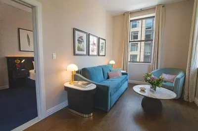 a living room with a blue couch and a table at The Frederick Hotel Tribeca in New York