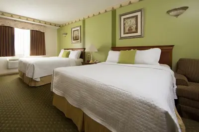 a hotel room with two beds and a chair at Villa Roma Resort and Conference Center in Callicoon