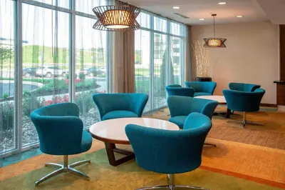 a waiting room with blue chairs and tables and windows at Fairfield Inn & Suites by Marriott Harrisburg International Airport in Middletown