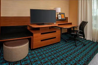 a hotel room with a desk with a monitor and a chair at Fairfield Inn & Suites by Marriott Harrisburg International Airport in Middletown