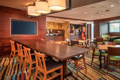 a dining room with a large wooden table and chairs at Fairfield Inn & Suites by Marriott Harrisburg International Airport in Middletown