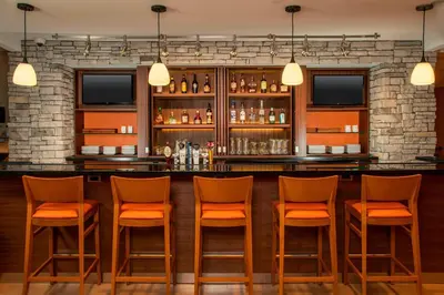 a bar with orange chairs in a room at Fairfield Inn & Suites by Marriott Harrisburg International Airport in Middletown