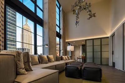 a living room with a couch and large windows at Moxy NYC Chelsea in New York