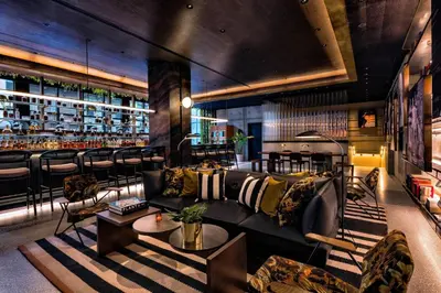 a living room with a couch and a bar at Moxy NYC Chelsea in New York