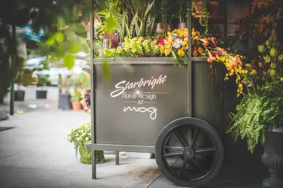 a cart filled with lots of flowers on a sidewalk at Moxy NYC Chelsea in New York