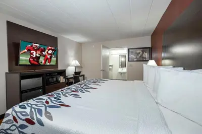 a hotel room with a large bed and a tv at Red Roof Inn Freehold in Freehold