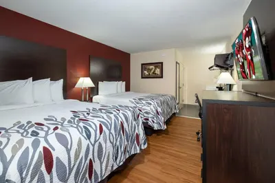 a hotel room with two beds and a flat screen tv at Red Roof Inn Freehold in Freehold